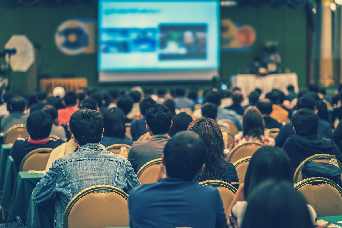 Rear view of Audience in the conference hall or seminar meeting which have Speakers are Brainstorming and talking on the stage, business and education about investment concept